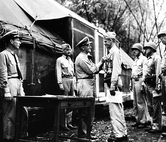 Visiting Guadalcanal on 30 September 1942, U.S. Navy Admiral Chester W. Nimitz, CinCPac, took time to decorate Lieutenant Colonel Evans F. Carlson, CO, 2d Raider Battalion; MajGen Vandegrift, in rear; and, from left, BGen William H. Rupertus, ADC; Col Merritt A. Edson, CO, 5th Marines; LtCol Edwin A. Pollock, CO 2d Battalion, 1st Marines; Maj John L. Smith, CO, VMF-223.