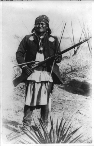 Scene in Geronimo's camp...before surrender to General Crook, March 27, 1886: Geronimo, full-length portrait standing, facing left, rifle at port