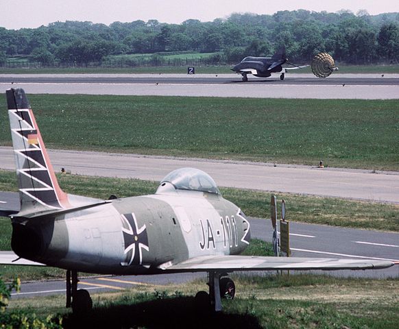 A retired German Luftwaffe Canadair CL13-B Mk6 Sabre at its former home base Wittmundhafen, Niedersachsen (Germany), 25 May 1989. The Sabre JA-111 was the personal aircraft of fighter ace Erich Hartmann, first wing commander of Jagdgeschwader 71 Richthofen (71st Fighter Wing) in 1959. The last Sabres left the wing in 1966, JA-111 is today preserved at the German Luftwaffe Museum at Berlin-Gatow. A JG 71 McDonnell Douglas F-4F Phantom II is landing in the background.