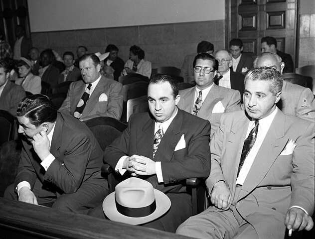 More details ARRAIGNED—Mickey Cohen and some of his henchman in court yesterday as they appeared for arraignment. Front from left, Edward Herbert, Mickey Cohen, Frank Niccoli. Back, James Rist, Eli Lubin and Louis Schwartz. Credit: Los Angeles Times - https://digital.library.ucla.edu/catalog/ark:/21198/zz0017r8s7, CC BY 4.0